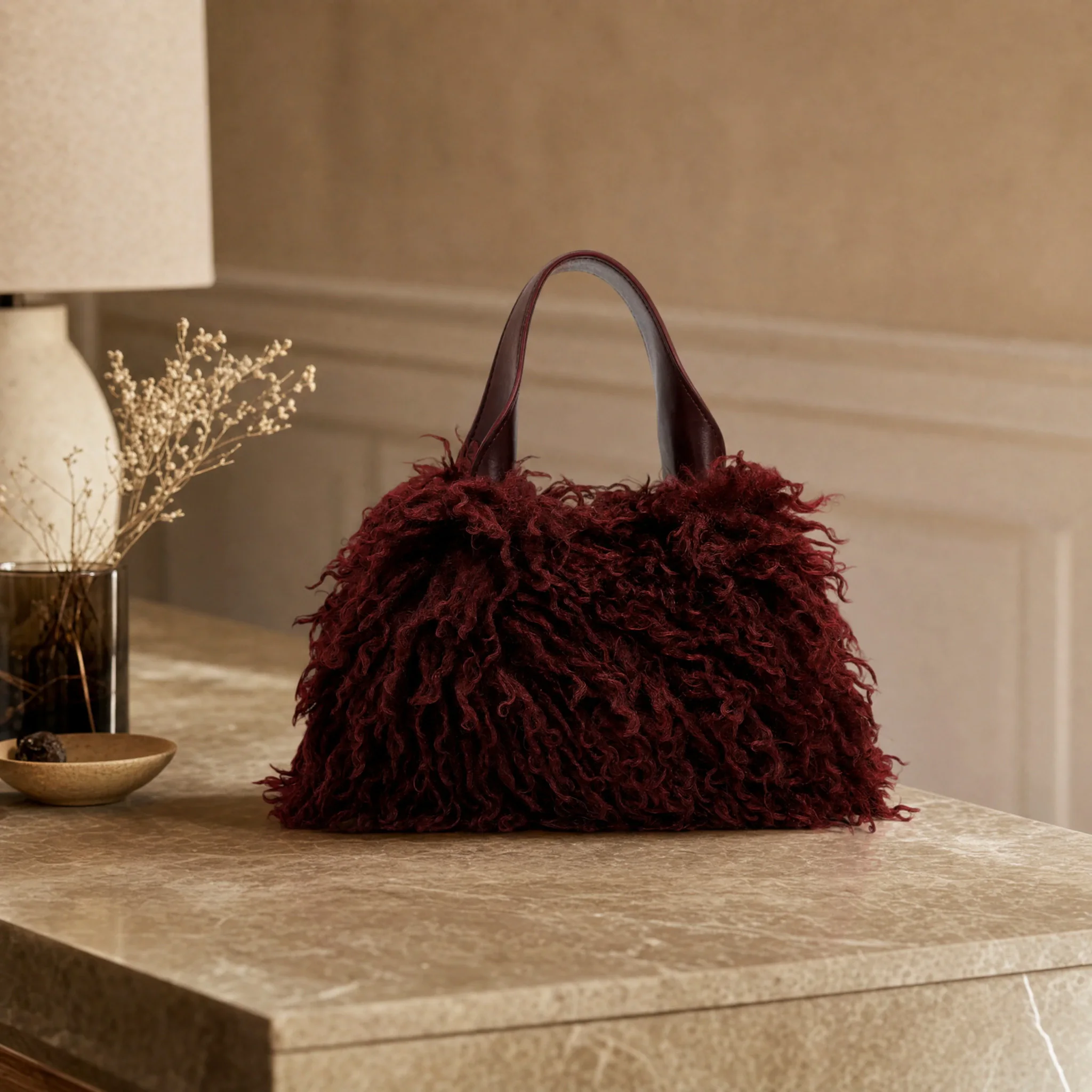 Mood image: burgundy handbag made of long fluffy material on a marble table