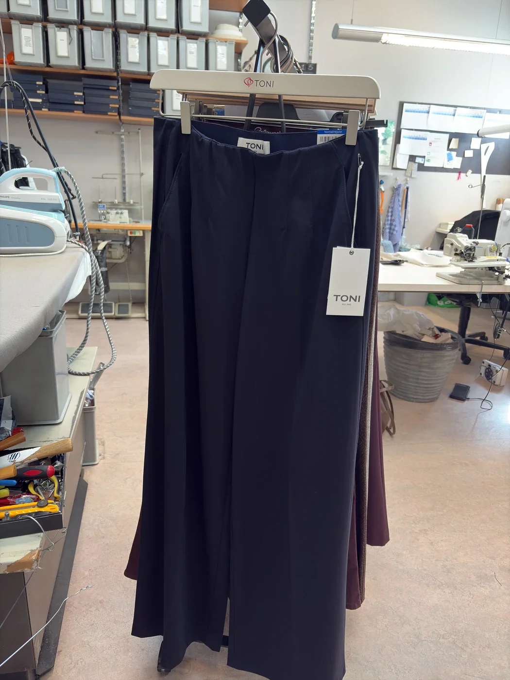 Aubergine trousers on a rack among other pants in the studio